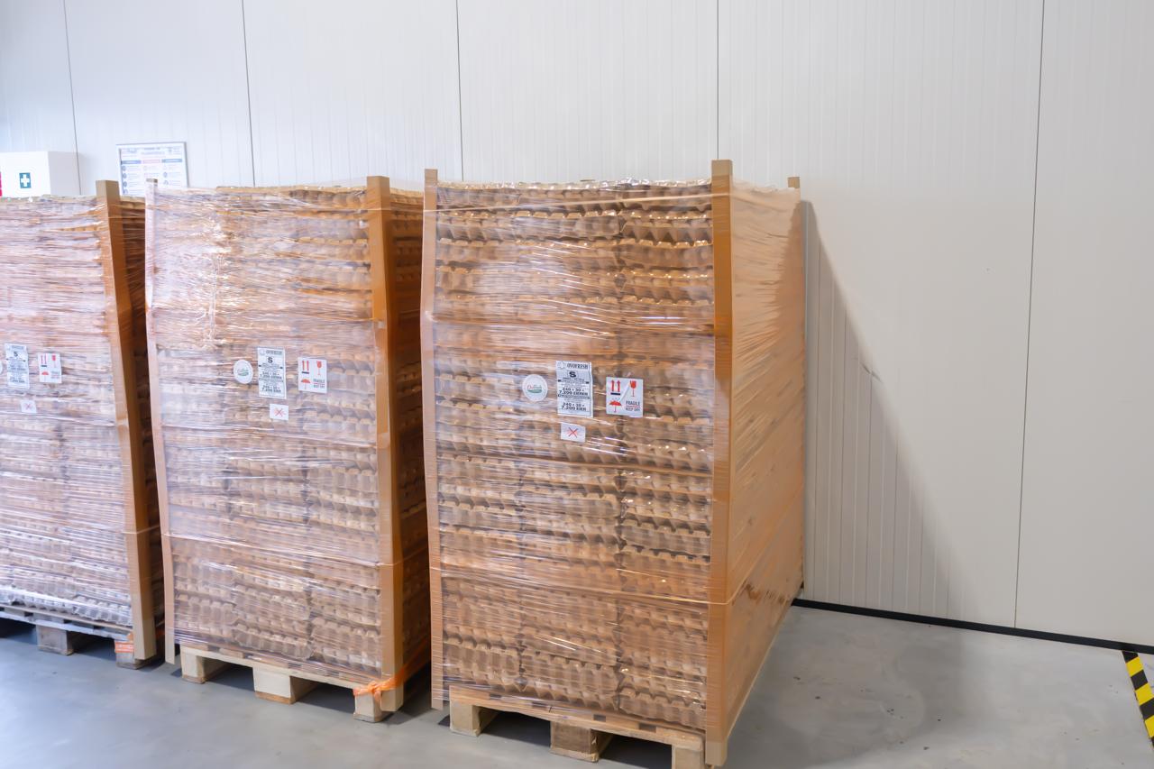 Met transparante folie omwikkelde pallets met bruine eierladen bij OVOFRESH